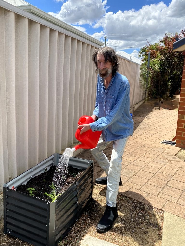 Mosaic client Karl watering the new garden bed at Derbarl house in Redcliffe.